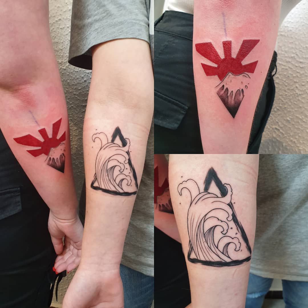 Matching tattoos of a wave and mountain within triangles, symbolizing strength, balance, and a shared journey